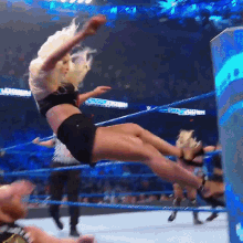 a woman is falling in a wrestling ring with a sign that says smackdown in the background