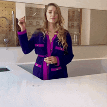 a woman in a purple and pink coat stands in front of a counter