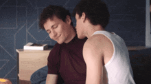 a man in a white tank top kisses another man