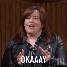 a woman wearing a leather jacket and a striped shirt is saying okay