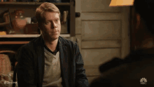 a man in a suit talks to another man in a scene from nbc 's show shrink