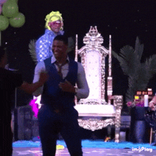 a man in a vest and tie is dancing on a stage in front of a chair