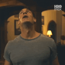 a man in a blue shirt is standing in a dark room with his mouth open and looking up .