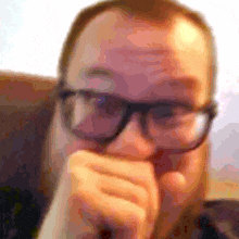a blurry picture of a man wearing glasses covering his mouth