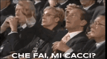 a group of people sitting in a row with the words che fai mi cacci written on the bottom