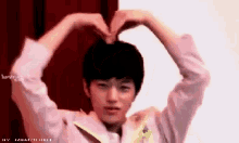 a young boy making a heart shape with his hands