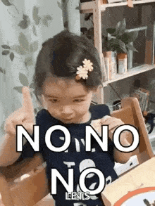 a little girl is sitting at a table and giving a thumbs up .
