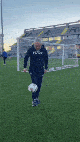 a man wearing a fc dk sweatshirt is kicking a soccer ball