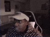 a man wearing a baseball cap is sitting in a chair .