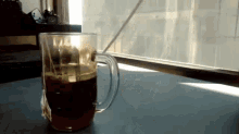 a cup of coffee with a straw in it is on a table in front of a window