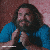 a man with a beard wearing a blue shirt with #minecraftmovie written on the bottom