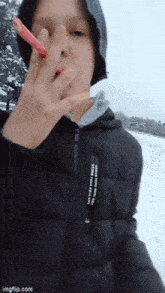a young boy in a black jacket is holding a pencil in his hand