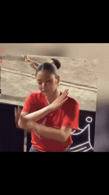 a woman in a red t-shirt is dancing in front of a mirror