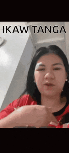 a woman with a bandage on her forehead is wearing a red shirt and holding something in her hand .