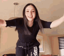 a young woman is dancing in a living room with her arms outstretched .