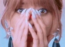 a close up of a woman with long white nails covering her face .