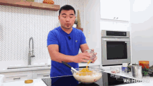 a man in a blue shirt is pouring a liquid into a bowl