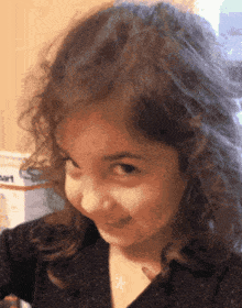 a little girl with a star necklace on her neck smiles