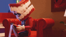 a man with fake teeth is sitting on a red chair