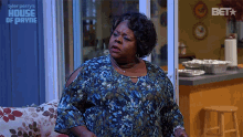 a woman sits on a couch in front of a sign that says house of payne