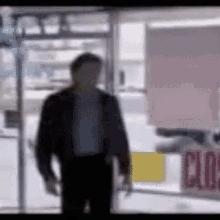 a blurry picture of a man walking into a store with a closed sign in the window