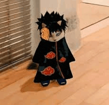 a cat dressed as obito from naruto is standing on the floor .
