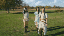 three women are standing in a grassy field wearing native american costumes