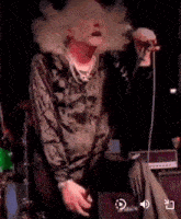a man is singing into a microphone while sitting on a stage