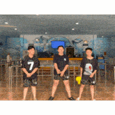 three young men standing in front of a wall with dolphins on it and one has the number 7 on his shirt