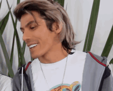 a man with long hair is smiling and wearing a white shirt with a picture of a cheetah on it