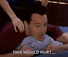 a man is laying on a bed with a woman holding his head and says this would hurt .