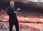 a man stands in front of a crowd in a stadium that says sky sports on the bottom