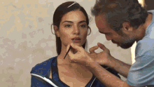 a man is applying lip gloss to a woman 's lips