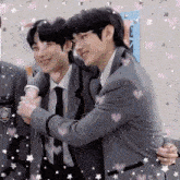a couple of men hugging each other in a room .