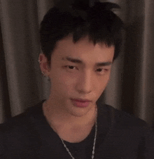 a close up of a young man wearing a necklace and earrings .