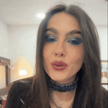 a woman wearing blue eyeshadow and a choker necklace
