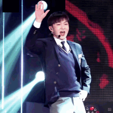 a man in a suit and tie stands on a stage with his hand in the air