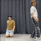a man is kneeling down next to another man who is standing on the floor .