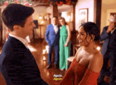 a man in a suit and a woman in a red dress are standing next to each other and the woman is saying again again