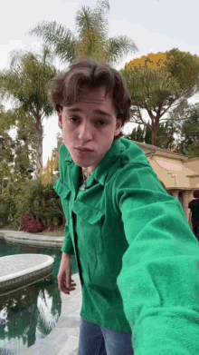 a young man in a green shirt taking a selfie