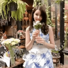 a woman in a blue and white dress is holding a vase of flowers .