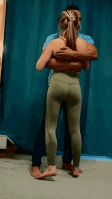 a man is hugging a woman in green leggings