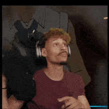 a man wearing a maroon shirt is sitting in a chair