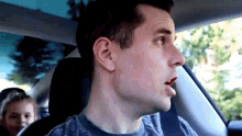 a man is driving a car with a girl behind him