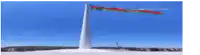 a very tall tower with a flag flying in the wind