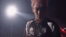 a man with pink hair is wearing a black and white jacket with skulls on it .