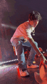a man in a white shirt and blue jeans is kneeling on a stage