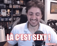 a man is smiling in front of a microphone with the words la c ' est sexy written above him