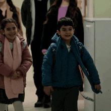 a boy and a girl are walking down a hallway