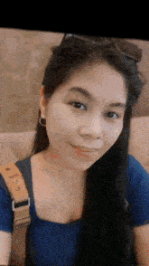 a woman wearing sunglasses and a blue shirt smiles at the camera